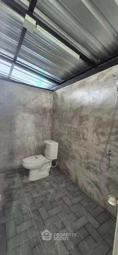 Modern industrial-style bathroom with exposed concrete walls and metal ceiling.