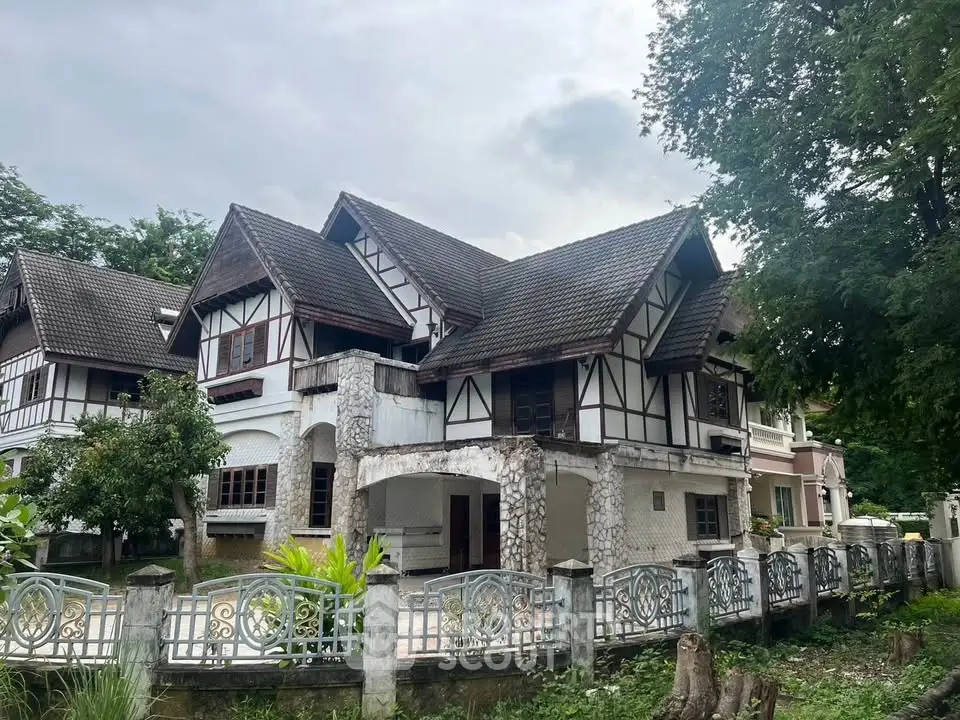 Charming Tudor-style house with intricate stonework and lush greenery