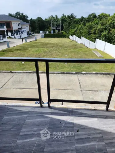 Spacious balcony with serene garden view in modern residential area.