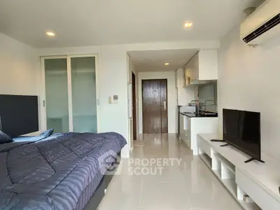 Modern studio apartment with sleek design, featuring a cozy bed, compact kitchen, and stylish TV setup.