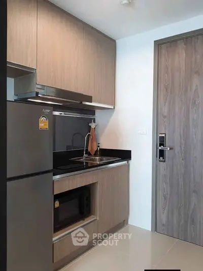 Modern compact kitchen with sleek cabinetry and stainless steel appliances in a stylish apartment.