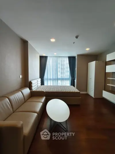 Modern studio apartment with cozy living area and large window for natural light.
