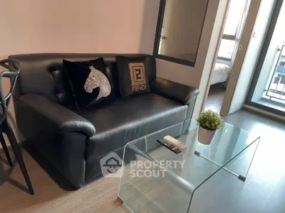 Modern living room with black leather sofa and glass coffee table in stylish apartment.