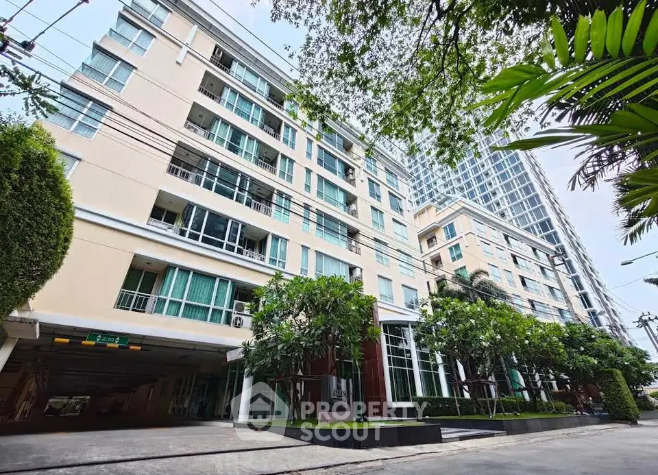 Modern condominium building with lush greenery and spacious entrance.