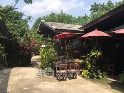 Charming rustic outdoor area with lush greenery and traditional wooden furniture, perfect for relaxation.