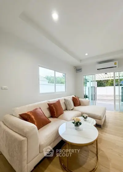 Spacious living room with elegant sofa and modern decor, featuring large windows and natural light.