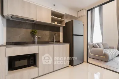 Modern kitchen with sleek cabinetry and open layout adjacent to cozy living room.