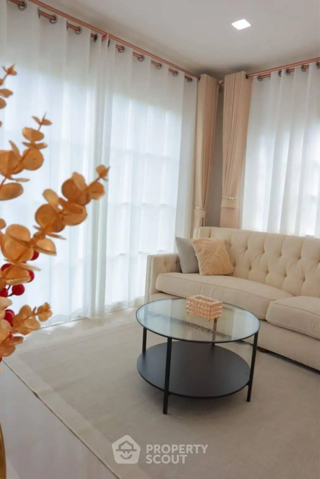 Elegant living room with plush sofa, sheer curtains, and modern glass coffee table.
