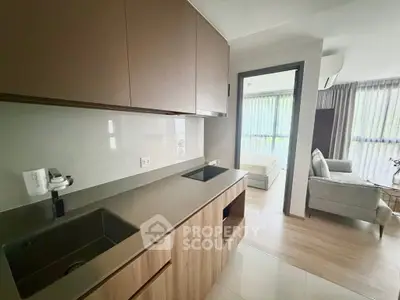 Modern open-layout kitchen with sleek cabinetry and integrated sink, leading to a cozy living area and bedroom.
