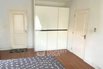 Spacious bedroom with modern wardrobe and wooden flooring