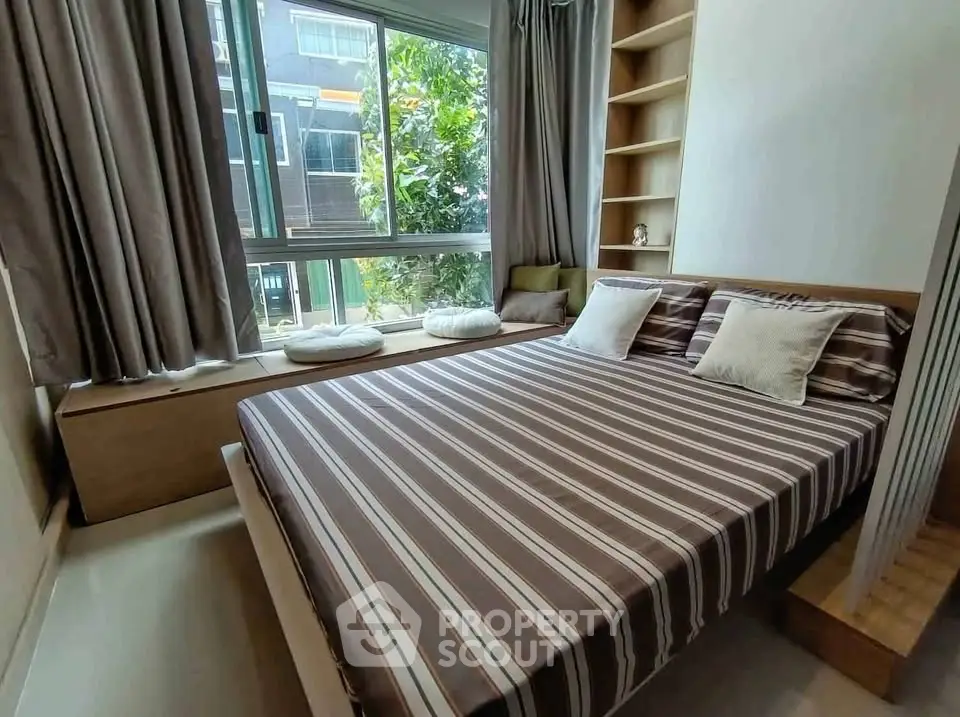 Cozy bedroom with large window and built-in shelving, perfect for natural light lovers.