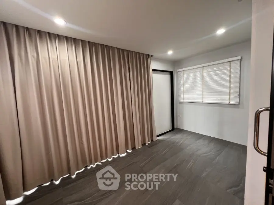 Spacious room with modern flooring and elegant curtains, ideal for versatile use.