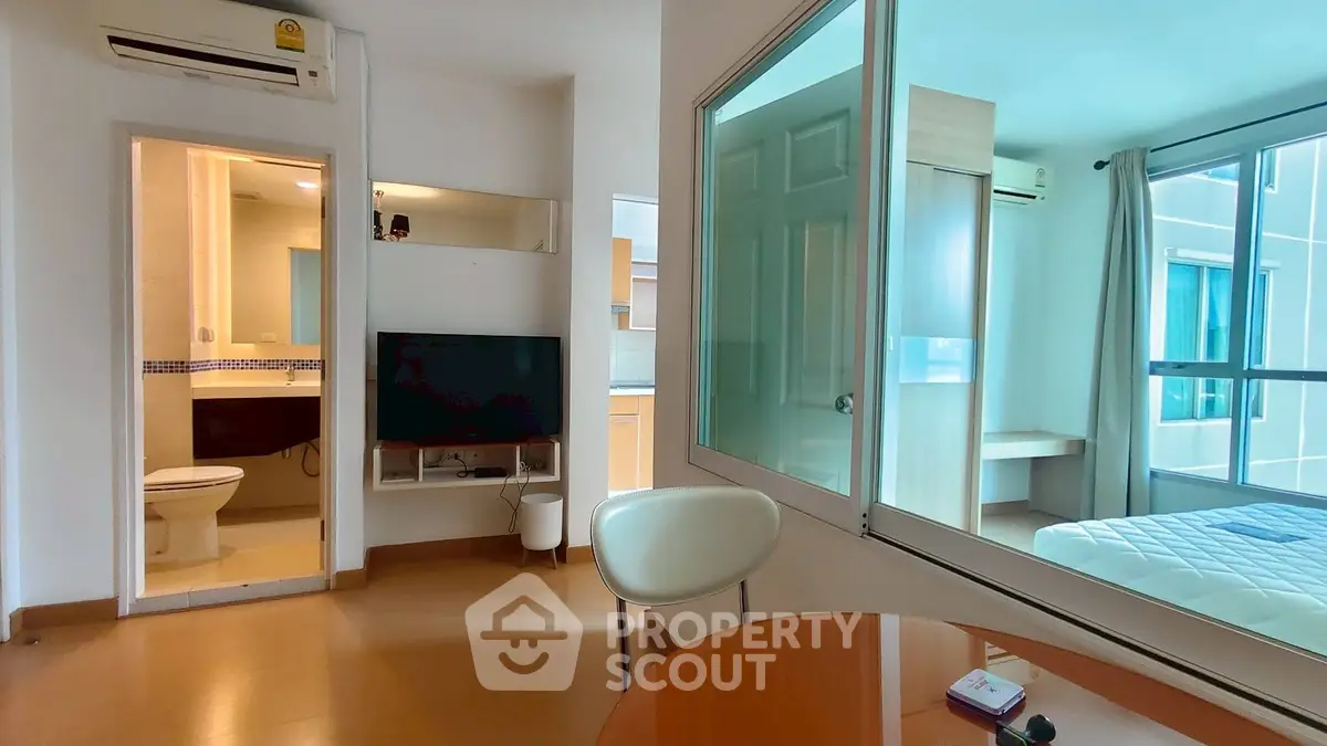 Modern apartment interior with open layout, featuring a cozy living area and a glimpse into the bedroom.