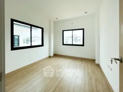 Spacious empty room with large windows and wooden flooring in modern home