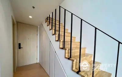 Modern staircase with sleek wooden steps and black railings in a stylish apartment