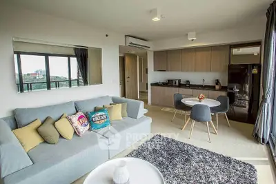 Modern open-plan living room with stylish kitchen and cozy seating area, featuring large windows and contemporary decor.