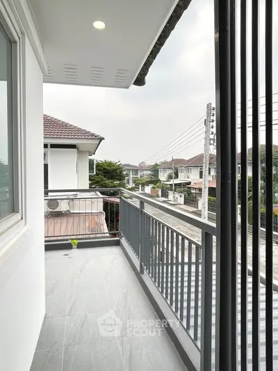 Spacious balcony with modern railing offering a serene neighborhood view, perfect for relaxation.