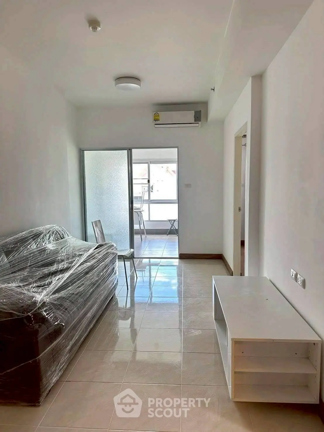 Modern living room with plastic-covered furniture and balcony access