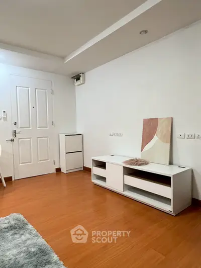 Minimalist interior with wooden flooring and white furniture in a cozy living space.