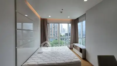 Spacious bedroom with large windows offering stunning city views in modern apartment.