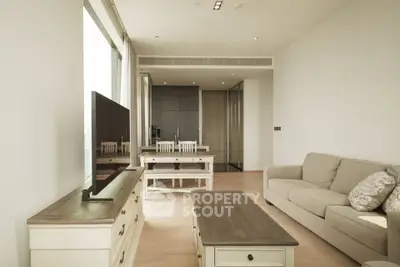 Modern living room with neutral tones, featuring a cozy sofa, sleek TV stand, and dining area with natural light.