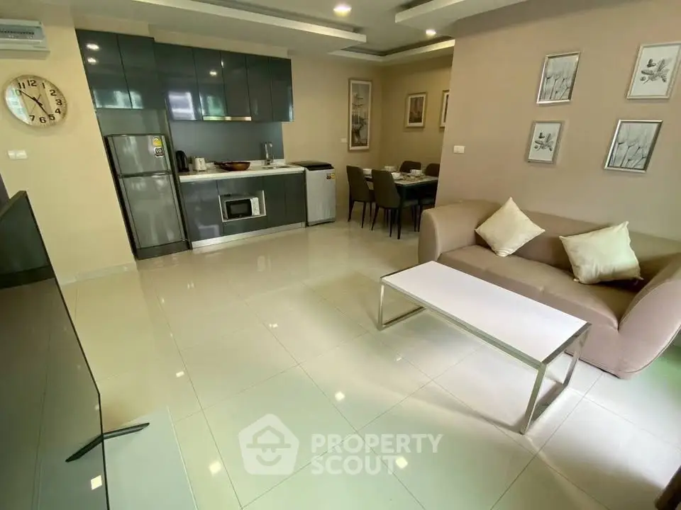 Modern open-plan living room with sleek kitchen and dining area, featuring contemporary furniture and stylish decor.