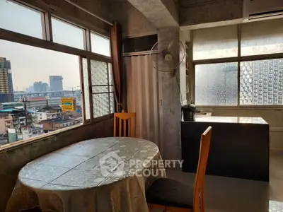 Spacious urban dining area with large windows offering city views, featuring a round table and modern decor.