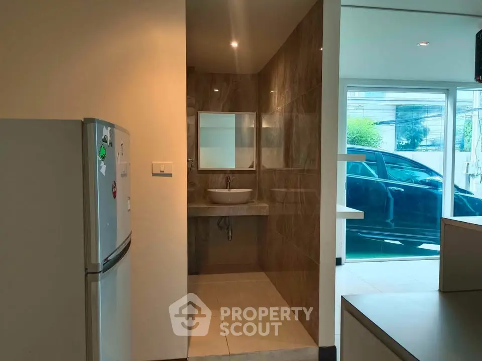 Modern kitchen with adjacent bathroom and view of parked car outside