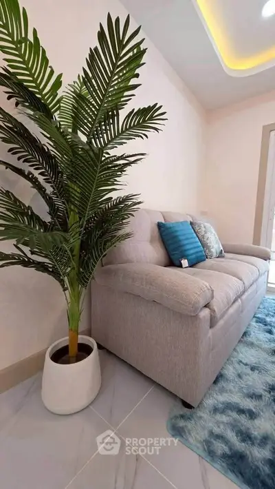 Stylish living room with plush sofa and decorative plant on elegant tiled floor.