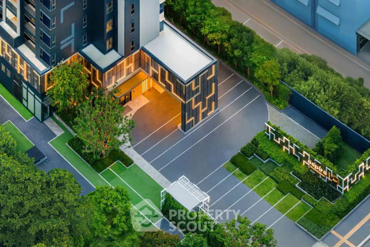 Modern building with landscaped entrance and parking area, showcasing sleek architectural design.
