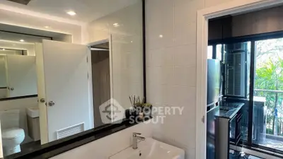 Modern bathroom with sleek design and balcony view, featuring a stylish sink and natural light.