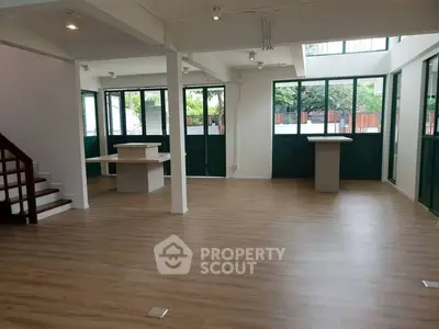 Spacious open-plan living area with large windows and wooden flooring