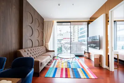 Modern living room with stylish decor and city view, featuring a colorful rug and elegant furniture.