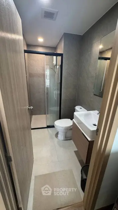 Modern bathroom with sleek design, featuring a glass shower enclosure and contemporary fixtures.