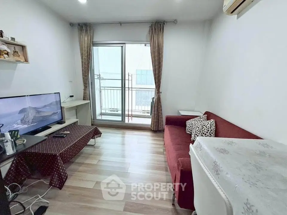 Cozy living room with balcony access, featuring a red sofa and modern TV setup.