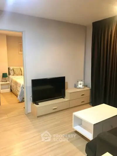 Modern living room with sleek furniture and TV, adjacent to a cozy bedroom.