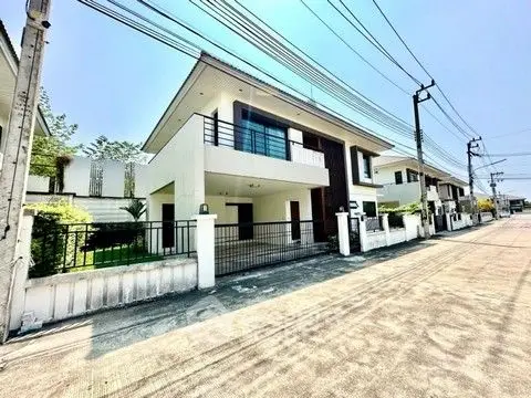 Modern two-story house with spacious balcony and gated entrance in a serene neighborhood.