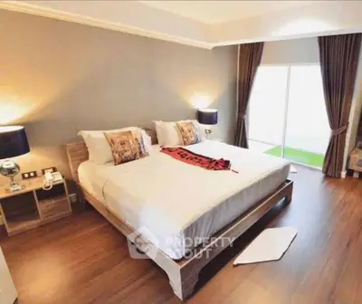 Spacious bedroom with modern decor and large window for natural light.