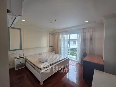 Spacious bedroom with balcony access and elegant wooden flooring in a modern apartment.
