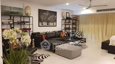 Spacious living room with elegant decor, featuring a large L-shaped sofa, zebra print rug, and tasteful art pieces, ideal for luxurious living.