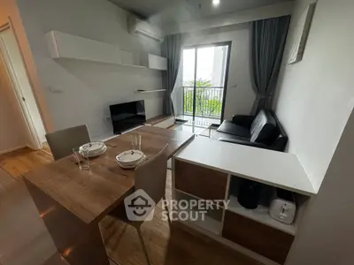 Modern living room with dining area and balcony view in stylish apartment.