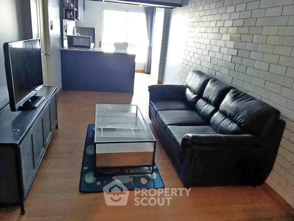 Modern living room with sleek black leather sofa and open kitchen layout