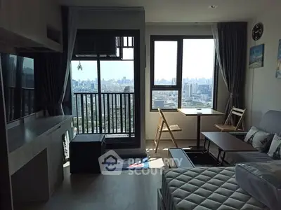Modern living room with city view, balcony, and stylish furniture in a high-rise apartment.