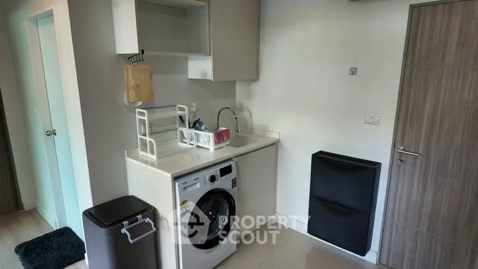 Modern laundry area with washing machine and storage in sleek apartment