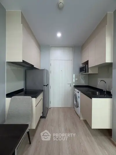 Modern compact kitchen with sleek cabinetry and integrated appliances in a stylish apartment.
