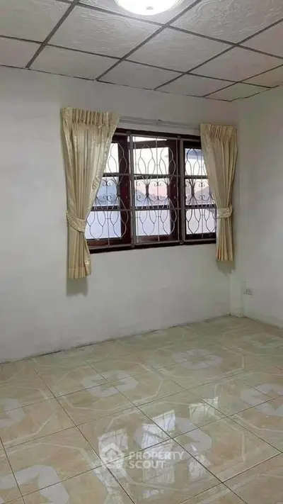 Spacious empty room with tiled floor and window view, ideal for customization.
