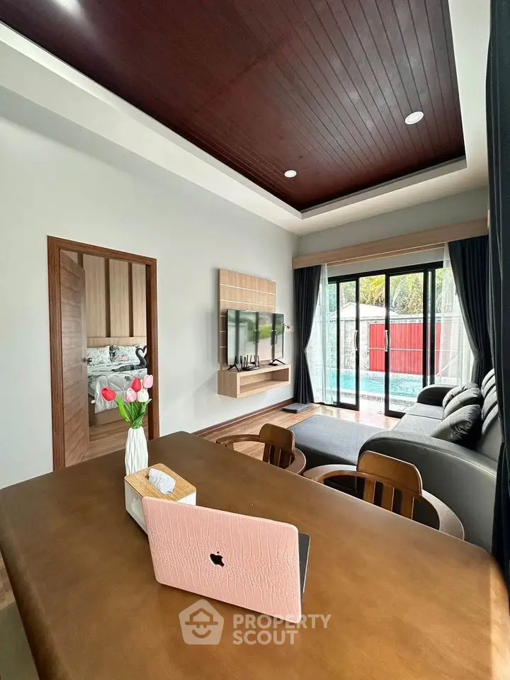 Modern living room with stylish decor, large windows, and pool view, featuring a cozy seating area and sleek wooden accents.