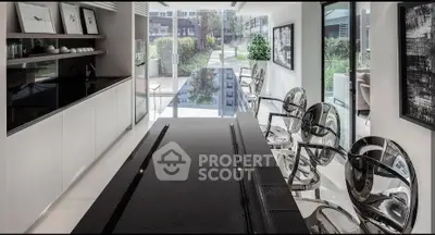 Modern kitchen with sleek black countertops and stylish transparent chairs, overlooking a lush garden view.
