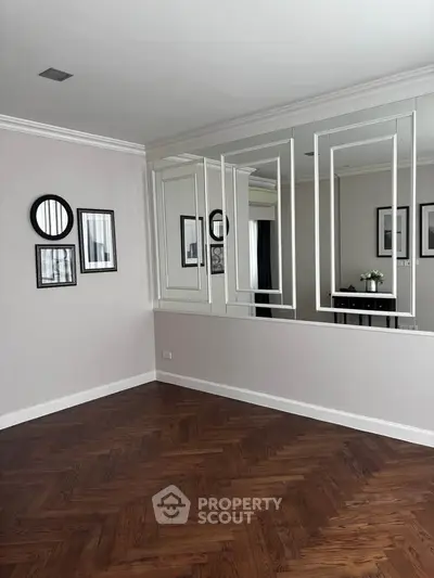 Elegant interior with mirrored wall and herringbone wood flooring, perfect for modern living spaces.
