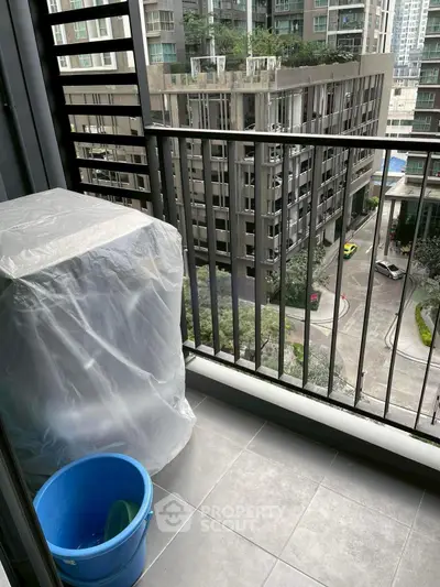 Modern balcony with city view, featuring a covered appliance and sleek railing design.